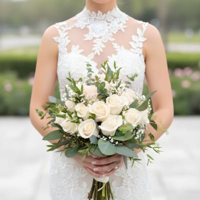 Bride holding a bouquet of white roses and greenery