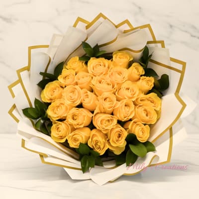 Bouquet of yellow roses wrapped in white paper with gold trim