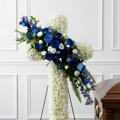 Blue and white funeral spray on a stand beside a casket