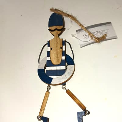 Wooden sailor ornament with blue and white details and a hanging twine loop