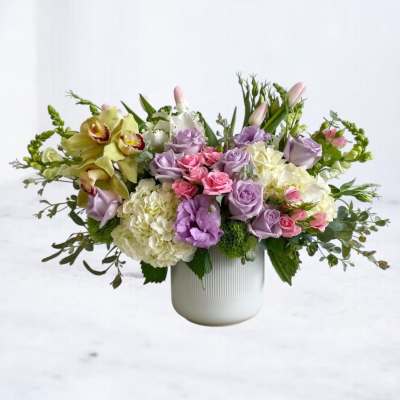 Mixed pastel bouquet in a white vase with roses, hydrangeas, and orchids