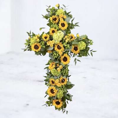 Sunflower cross arrangement with green filler on a white background