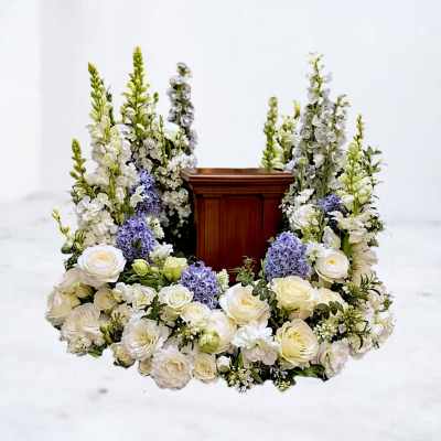 White and lavender floral wreath around a wooden urn