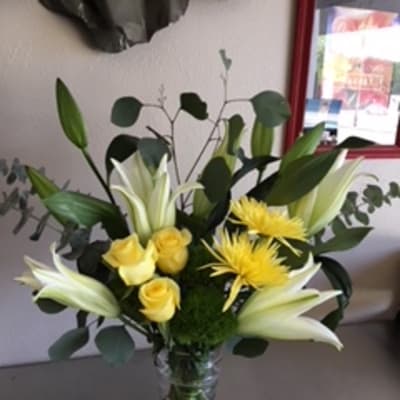 Yellow roses and white lilies in a glass vase