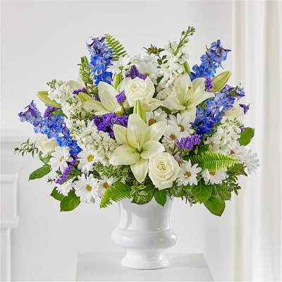 White lilies, roses, daisies, and blue flowers in a white vase