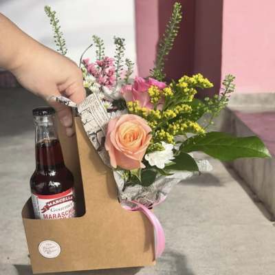 Bouquet with pink and peach roses in a kraft gift box beside a maraschino cherry bottle
