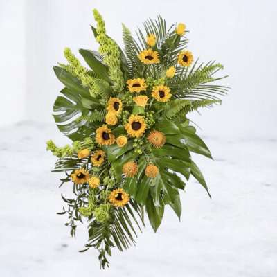Yellow sunflower arrangement with tropical greenery and orange accent blooms
