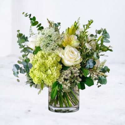 White and green floral arrangement in a clear glass vase