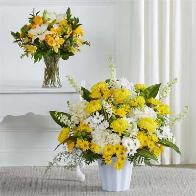 Yellow and white flower arrangements in a vase and urn