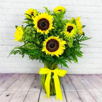 Sunflower bouquet in a glass vase with a yellow ribbon