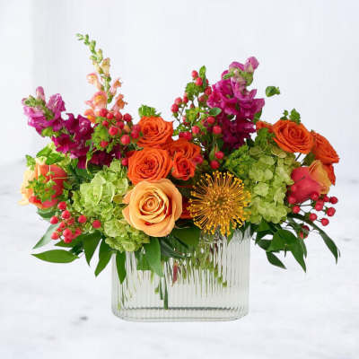 Colorful bouquet of roses, hydrangeas, and snapdragons in a clear glass vase