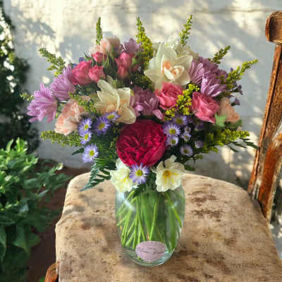 Mixed bouquet of pink, purple, and white flowers in a glass vase