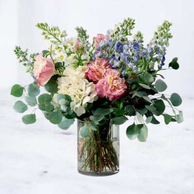 Bouquet of pink, white, and blue flowers in a clear glass vase