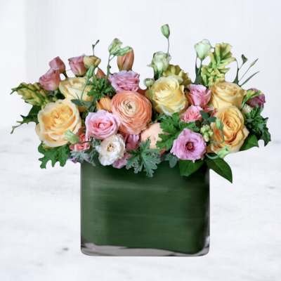 Mixed pastel bouquet in a dark green square vase