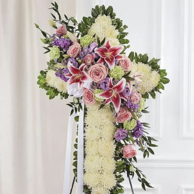 Standing floral cross with pink roses and lilies on a white easel