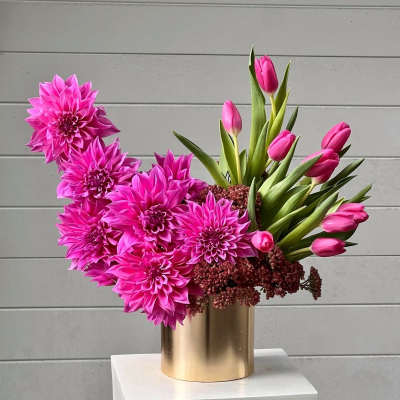 Pink dahlias and tulips arranged in a gold vase