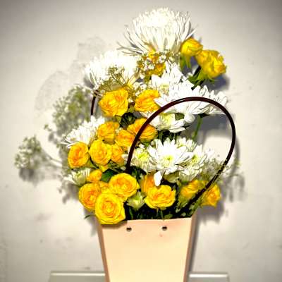 Yellow roses and white daisies in a peach tote-style container