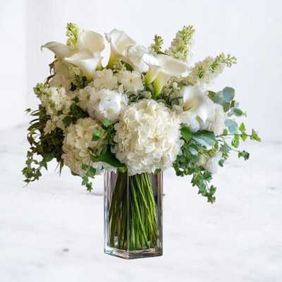 White calla lilies and hydrangeas in a clear glass vase