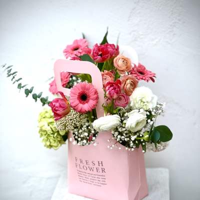 Pink and white mixed flower arrangement in a pink gift bag