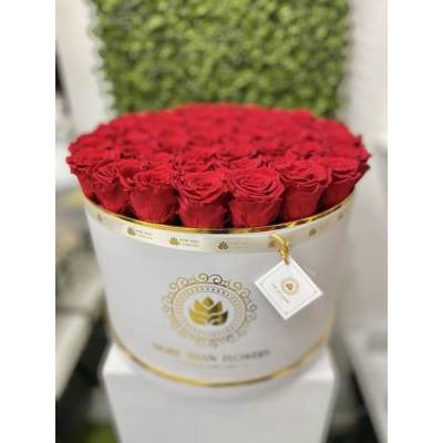 Round white hat box filled with tightly packed red roses