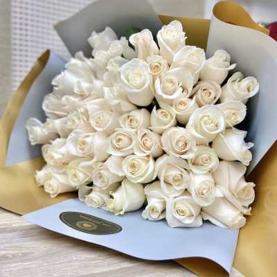 Large bouquet of cream roses wrapped in blue and gold paper