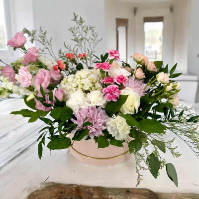 Pink and white mixed flower arrangement in a round blush box