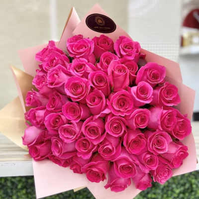 Large bouquet of bright pink roses wrapped in pale pink and beige paper