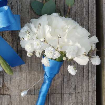 White boutonniere with blue ribbon wrap and small white filler flowers