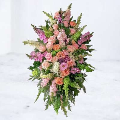 Large standing spray of pink and peach flowers with green accents