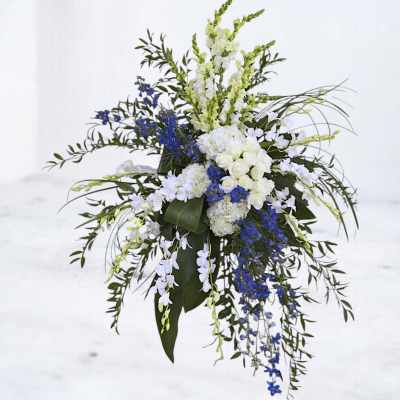 Tall floral spray with white and blue flowers and cascading greenery