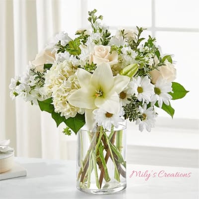 White lilies, roses, hydrangeas, and daisies in a clear glass cylinder vase