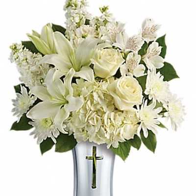 White lilies and roses arranged in a silver vase with a cross