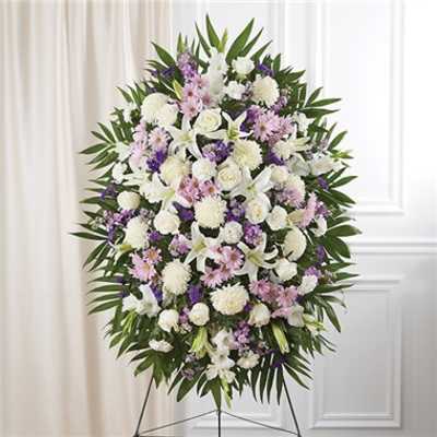 Standing funeral spray of white and lavender flowers on an easel