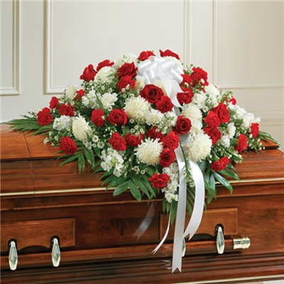 Red and white floral casket spray with ribbon on a wooden coffin