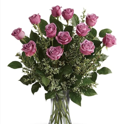 Pink roses arranged in a clear glass vase with mixed greenery