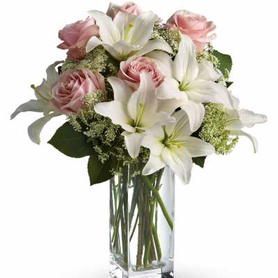 Pink roses and white lilies arranged in a clear glass vase