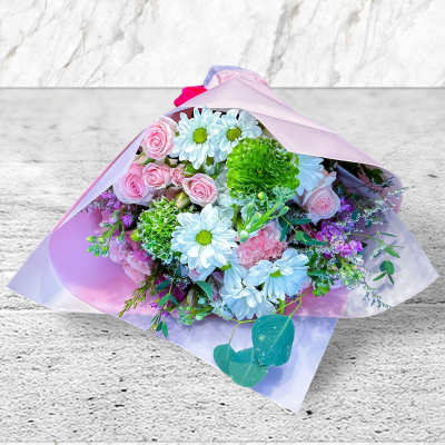 Bouquet of pink roses, white daisies, and green carnations wrapped in pink paper