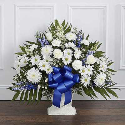 White floral standing spray with a blue ribbon on a pedestal base