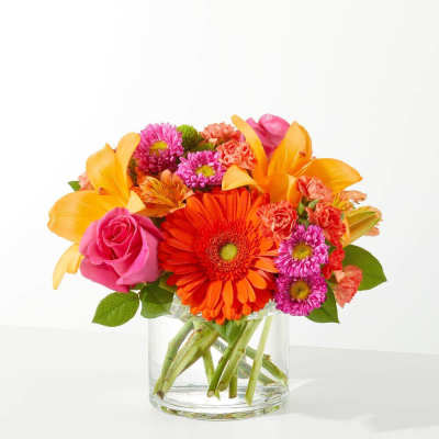 Bright mixed bouquet in a clear glass vase with orange, pink, and purple flowers