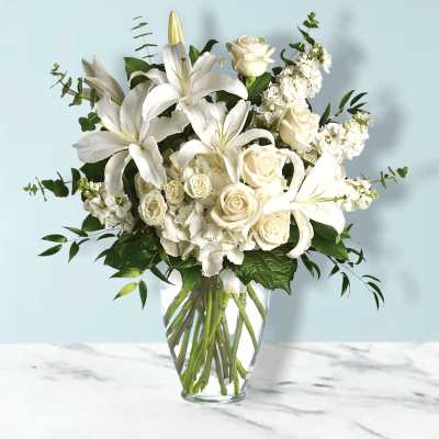 White lilies and roses arranged in a clear glass vase