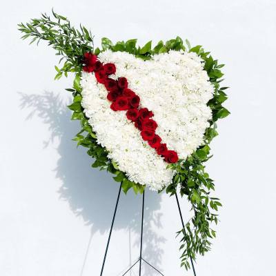 Heart-shaped white floral spray with a red rose diagonal on a stand
