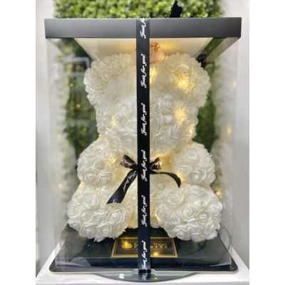 White rose teddy bear with string lights in a clear display box with black lid and ribbon