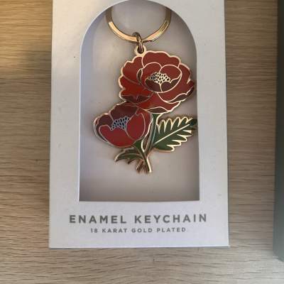 Red floral enamel keychain in a white retail box
