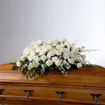 White rose casket spray on a wooden coffin