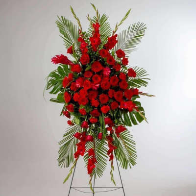 Tall standing spray of red roses and red flowers with palm fronds