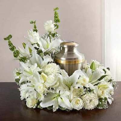 White floral funeral arrangement around a metal urn