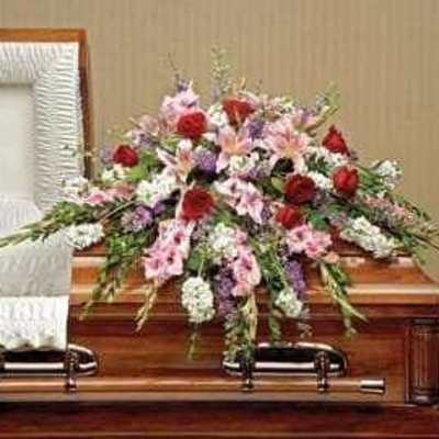Floral spray on a wooden casket with pink, red, and white flowers