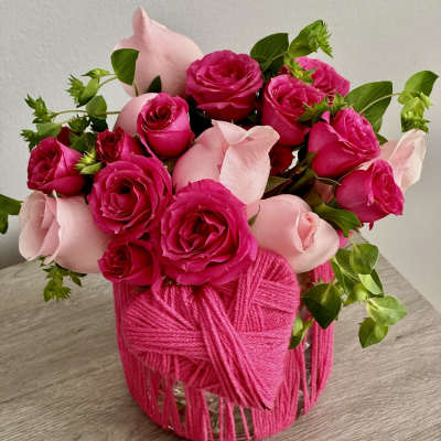 Pink and hot pink roses arranged in a yarn-wrapped vase