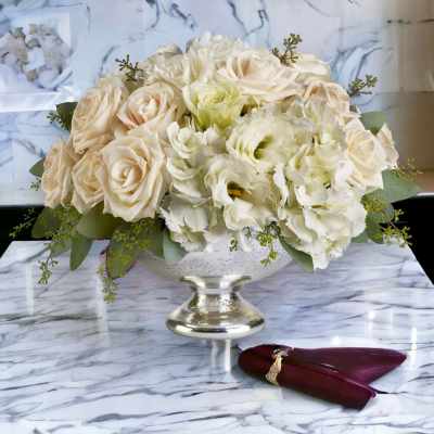 Cream rose and white flower arrangement in a silver pedestal vase