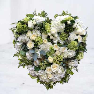 Heart-shaped floral arrangement of white roses and hydrangeas with green accents